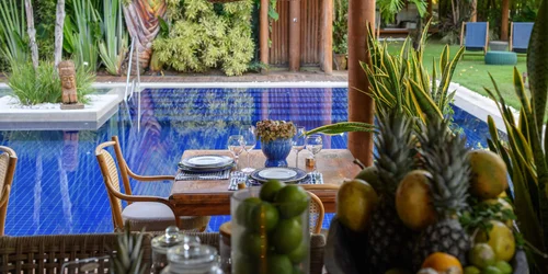 Mesa posta à beira da piscina com frutas tropicais